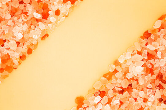 Pink Himalayan salt crystals border frame on yellow background with copy space
