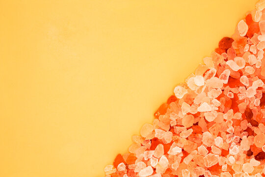 Pink Himalayan salt crystals on yellow background with diagonal copy space