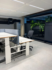 Fototapeta premium An open-plan contemporary office layout incorporates a lush greenery zone with potted plants and vertical garden, creating a calm and productive atmosphere. Startup workspace inspiration, HR wellness