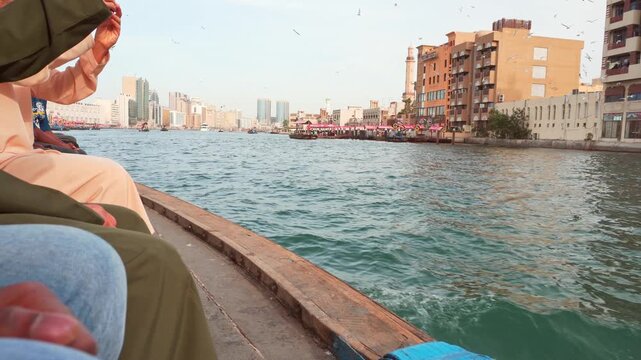 Dubai, UAE - 17th january, 2026: Traditional wooden abra crossing Dubai Creek. Tourist local passengers using smartphones with the historic Deira skyline and modern towers in the background