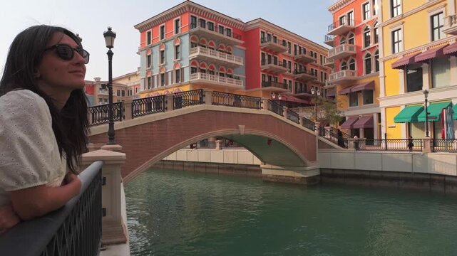 Doha, Qatar - 20th january, 2026: Woman traveler enjoy canal views in Qanat Quartier Pearl Qatar colorful Venice style architecture with canals bridges luxury waterfront lifestyle travel destination