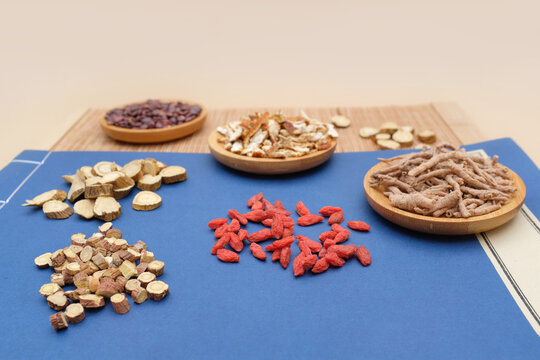 Various traditional Chinese medicinal herbs arranged on a blue cloth and bamboo mat