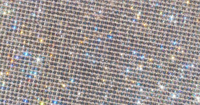 Rotating Sparkling Rhinestone. Macro video of faceted crystals sparkling intensely with smooth rotational camera movement on white surface.
