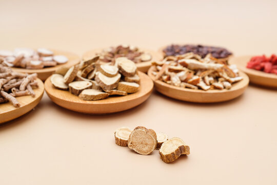 Various dried traditional Chinese medicinal herbs sliced and arranged on wooden trays