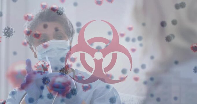 Animation of virus cells and biohazard over caucasian fmale doctor in face mask holding syringe