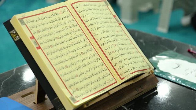 Close up detail of an open holy book Quran on a lectern showing the beautiful Arabic calligraphy for religious studies and spiritual reflection at a mosque or home during day