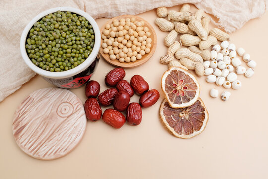 A flat lay composition of mung beans, soybeans, peanuts, red dates, coix seeds, and dried citrus peel as traditional Chinese health food ingredients