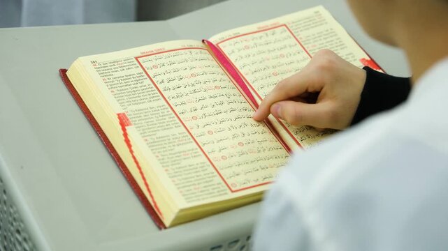 High angle view of a teacher and student studying the holy Quran together for religious education and memorization at an islamic school or mosque during a sunny day
