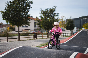 Fototapeta premium A young girl riding a pink bicycle on a paved bike path in a suburban neighborhood