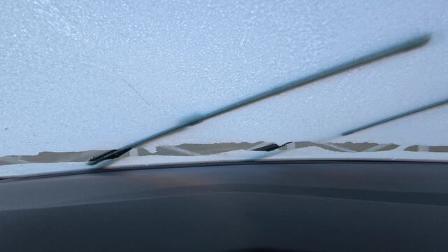 Frozen windshield, wiper on. Frozen windshield. Car windshield in winter.