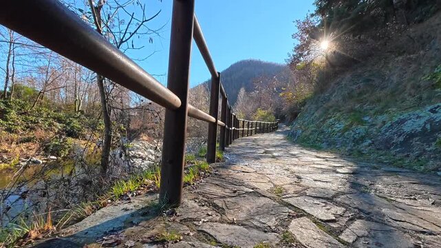 A low-angle view of walking along a rocky mountain path along river, Italy
