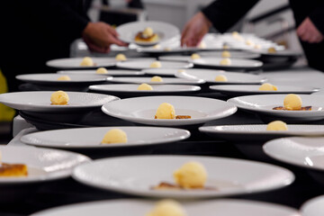 Multiple dessert plates being prepared in a professional restaurant kitchen before service in a...