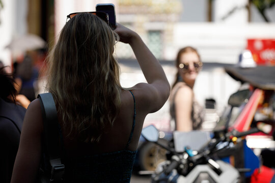 Woman with blonde hair walking, unposed movement, nonverbal communication, body language outdoors, shoulder skin hair, rear view, Tha Chang.