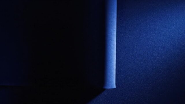 A close-up shot of a cylindrical object standing upright against a dark blue background with a beam of light casting a shadow, creating a moody atmosphere.