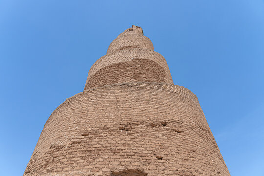A striking minaret, built with layered brickwork, commands attention against the vibrant blue sky in Abu Dulaf, Iraq