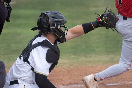 Young high School baseball catcher with the ball in his glove and the batter swinging