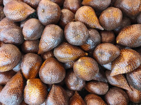 Fresh snake fruits or salak piled at a traditional market for healthy organic food and exotic grocery shopping concept