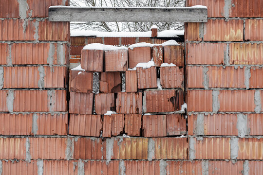 An old brick wall with a window blocked with bricks