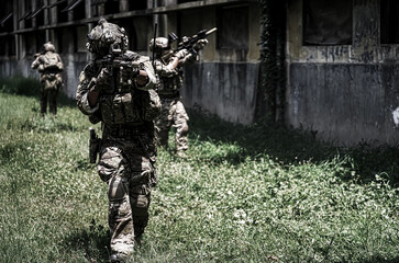 Obraz premium Soldiers in tactical gear advancing through overgrown terrain during training exercise