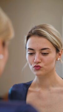 A young woman displays various beautiful facial expressions while admiring her beauty in the reflection of a mirror