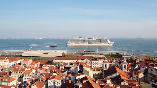 Alfama Historic Neighborhood and Big Cruise Ship Leaving Port on Sunny Day. Red Roofs and White Houses. Vibrant Lisbon Old Town, Portugal. View from Miradouro das Portas do Sol