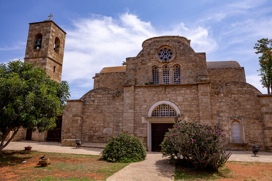 Historic exterior view of the Monastery of Saint Barnabas in Famagusta, Northern Cyprus, showcasing ancient stone architecture, a domed church, and dramatic sky.


