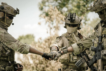 Special forces soldiers in camouflage gear fist bumping in solidarity outdoors