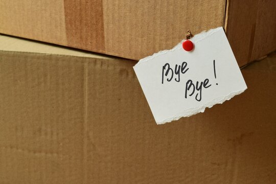 A handwritten "Bye-Bye" message on a card is attached to a cardboard box