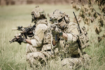 Fototapeta premium Special forces soldiers in camouflage gear advance cautiously through tall grass