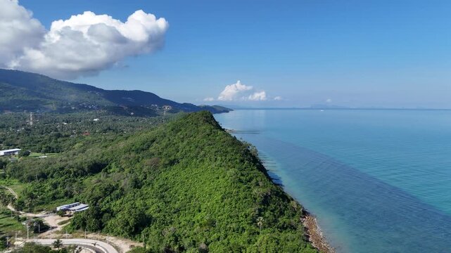 Flying drone over exotic jungle hill towards the bright blue horizon of Samui island. Thailand