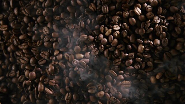 Industrial roasting process of coffee beans with smoke in roaster, top view.