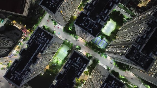 Top-down drone image of Hanoi residential complex showing illuminated courtyards, green spaces, and internal roads forming a structured geometric city layout at night.