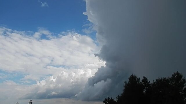 Natural sky with thunderstorm, threatening stormy and rainy clouds, white Cumulus and Altocumulus over trees - weather change and upcoming clearing. Topics: weather, cloudscape, cloud types