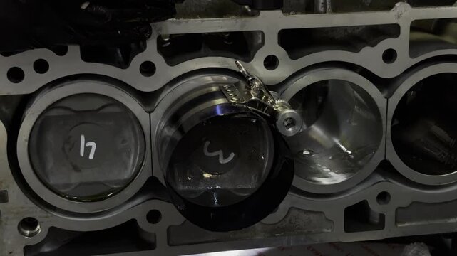 Close-up of mechanic installing a piston into a car engine block.