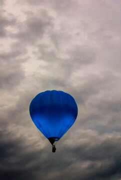 A blue hot air balloon with the Barclays logo is floating in the sky.