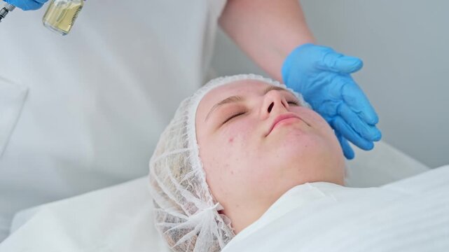 A beautician applies lotion to a woman's face during her facial cleansing treatment. This session takes place in a spa setting with a focus on skincare.