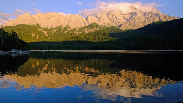 Stunning landscape video of the sunset over Eibsee lake with clear mountain reflections and the Zugspitze massif in the Bavarian Alps, Germany.
