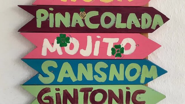 Colorful wooden signs pointing to different cocktails, ideal for a summer party background