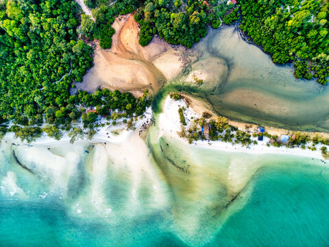 Aerial view of the shoreline where turquoise waters meet the sandy beach and lush greenery, Preah Sihanouk, Sihanoukville, Cambodia.