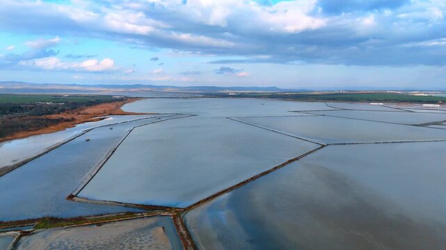 Geometric pattern of salt evaporation ponds from above. Aerial perspective showing the angular shapes of salt pans and surrounding wetlands.