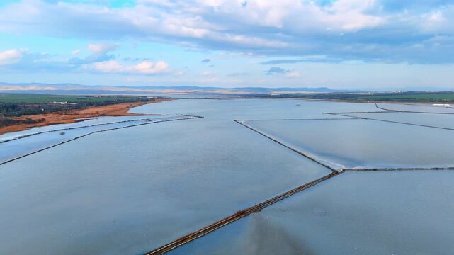 Drone shot of salt evaporation reservoirs and dikes. Overhead view of water management infrastructure for sea salt production.