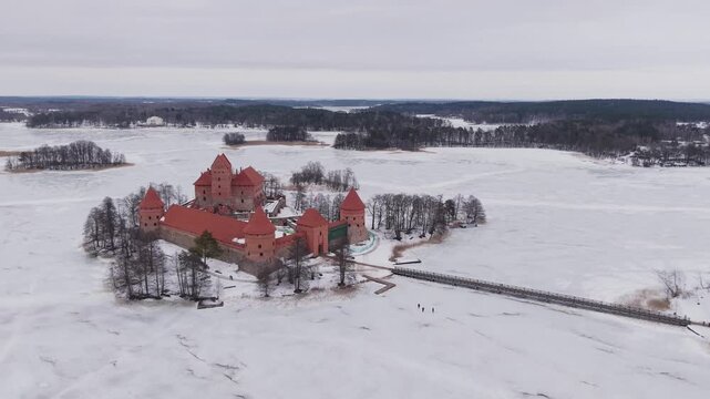 Aerial view of the magnificent Trakai Island Castle surrounded by the frozen Lake Galve, creating a stunning contrast of red brick and white ice, Trakai, Lithuania.