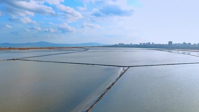 Symmetrical salt evaporation basins stretching to the horizon. Aerial perspective of large scale industrial salt production ponds under sky.