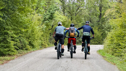 Obraz premium Three friends cycling together on a forest road enjoying mountain biking and outdoor adventure