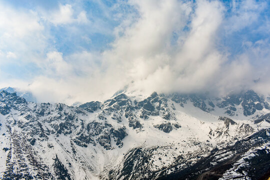 Cloud-covered snow peaks in the Himalayas, dramatic high-altitude mountain landscape, North Sikkim, India.