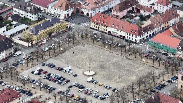 Aerial view of buildings with orange rooftops, parking lots with cars, and a large square, creating a vibrant urban landscape, Neuf-Brisach, Grand Est, France.