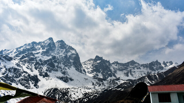 Snow-covered Himalayan mountains rising above forested slopes under cloudy sky in scenic North Sikkim landscape.