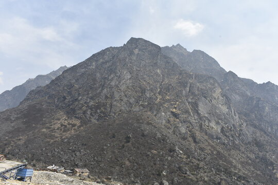 Steep rocky Himalayan mountain with rugged terrain and cloudy sky overlooking remote high altitude landscape in North Sikkim.