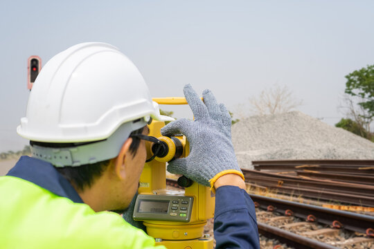Close-up of a civil engineer using a total station theodolite for land surveying at a railway construction site, ensuring precision for track alignment and infrastructure.