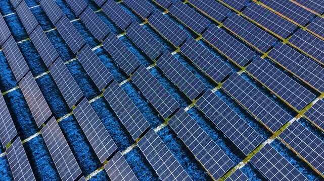 Pattern of solar panel rows in winter landscape. High angle aerial view of solar arrays arranged in a repetitive pattern over ground with snow.